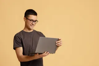 Un hombre joven sonrÃe al usar su MacBook de Apple